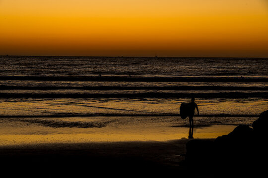 silhouette of a surfer walking on the beach