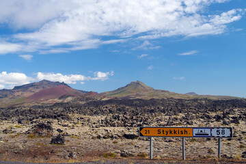 View on direction sign to ferry stykkish, volcanic surreal rugged lava landscape and volcano cone background - Iceland