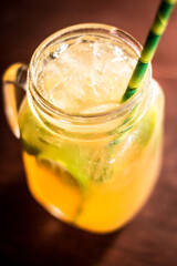 Moscow mule cocktail alcohol drink beverage with lemon slices straw ice and bokeh background on a wooden table