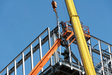 Ouvriers travaillant en hauteur sur un chantier de construction - obrazy, fototapety, plakaty