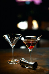 two wine glasses filled with alcoholic cocktail and empty in the bar on a dark background