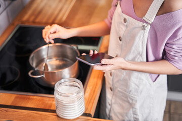 Woman looking recipe at her smartphone while cooking