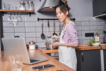 Woman covers pan with a lid while looking attentively recipe