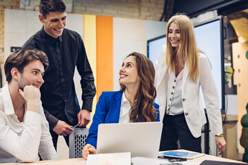Happy young woman manager surrounded by colleagues in the office