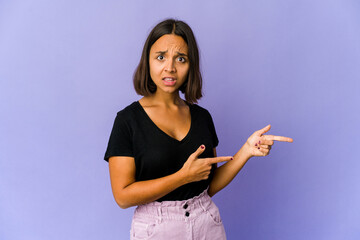 Young mixed race woman shocked pointing with index fingers to a copy space.