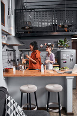 Girls having fun while cooking together at kitchen