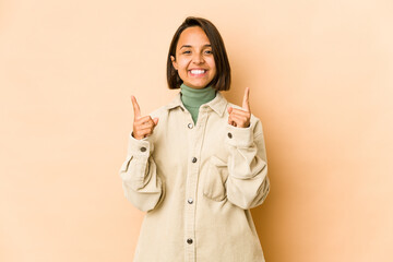 Young hispanic woman isolated indicates with both fore fingers up showing a blank space.