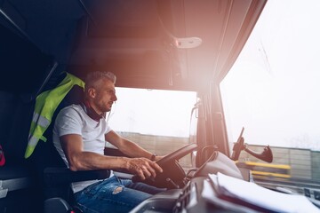 Handsome driver at the wheel of a truck at work. Semi Truck Driver Job. © Daniel Jędzura
