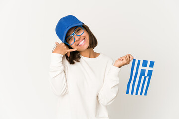 Young hispanic mixed race woman holding a greece flag showing a mobile phone call gesture with fingers.
