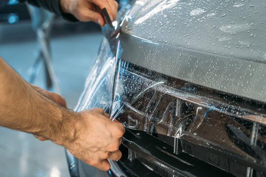 Process of installing of Paint Protection Film or PPF on new car in professional auto Detailing Center. Thin polyurethane film or polymer as protective skin from scratches and rock chips.