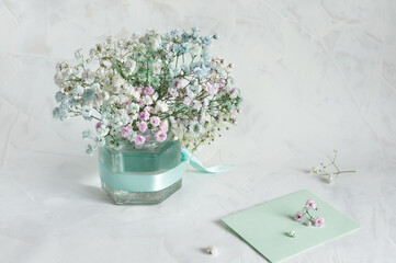 Bouquet of small flowers of gypsophila in pastel colors on a light gray marble background with a small carpet. Selective focus. Copy space for text