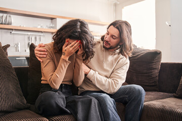 Fototapeta na wymiar Husband consoles his wife and embracing shoulders at sofa