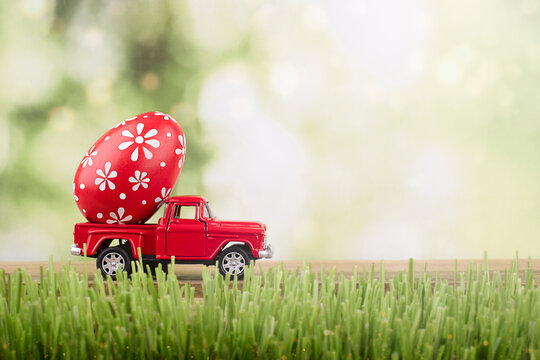 red toy car carrying a decorated easter egg