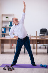 Old businessman employee doing sport exercises in the office