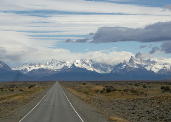 Asphalted road with the peaks of a rocky and snowy mountain on the horizon. Fitz Roy mountain in Argentina horizontal Photograph