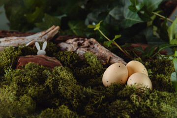 Creative Easter composition of Easter eggs and bunny rabbit in the mossy forest woods background....