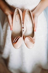 The bride is holding white shoes. Preparing for wedding.