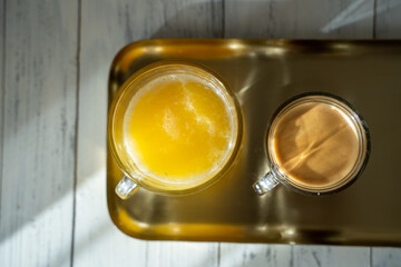 Obraz na płótnie Canvas a cup of coffee with glass of orange juice on a gold tray. sunny morning. top view.