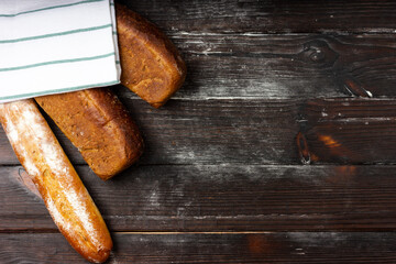 Fresh rustic bread on a dark table. Black bread, baguette top view.