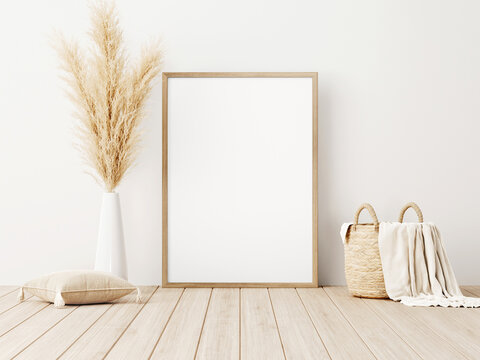 Vertical frame mockup standing on wooden floor in living room interior with dried pampas grass, woven basket, blanket and pillow with tassels on white wall background. 3d rendering, 3d illustration