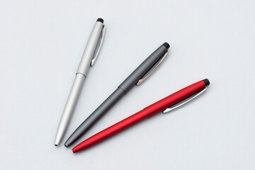 Three metallic pens on the gray background.