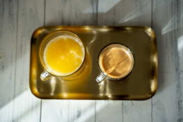 a a cup of coffee with glass of orange juice on a gold tray. sunny morning. Top view. High quality photo