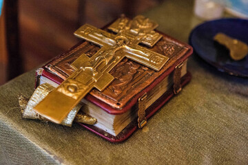 old bible with a lock on the binding and a cross is on the book.