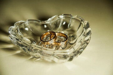 Wedding rings in a crystal vase in shape of a heart.