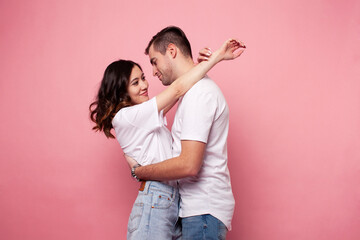 young cheerful caucasian couple together having fun on pink background, guy ang girl modern relationship, lifestyle people concept