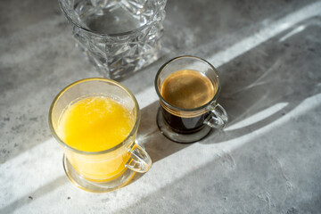 a a cup of coffee with glass of orange juice and glass of water on a table. sunny morning. Gray background. Copy space for a text. Top view. High quality photo
