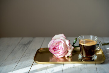 a a cup of coffee with a rose on a gold tray. Romantic coffee. sunny morning. Copy space for a text. High quality photo
