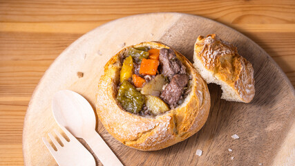 Delicious tasty hot warm homemade take away delivery beef stew red wine gravy soup sauce meal food meal with vegetable carrot potato pepper serve with bread bowl disposable wood cutlery spoon fork