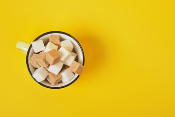 cane brown and white sugar cubes in yellow cup on yellow background