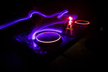 DJ console deejay-mixing desk in dark with colorful light. Mixer equipment entertainment DJ station.