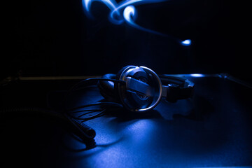 Dj music club concept. Close up headphones on dark background with colorful light.