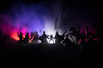 Medieval battle scene with cavalry and infantry. Silhouettes of figures as separate objects, fight between warriors on sunset foggy background.