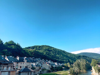 A panoramic view of a small old French village surrounded by nature during a summer day over a blue...