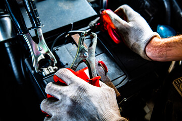 Male hands attaching clips to a car battery, close-up.