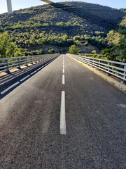 Straight highway during summertime with mountains and forests in the background. Nobody around.