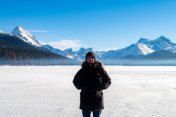 Fototapeta na wymiar Maligne Lake, Canada - december 2020 : young man standing on the frozen lake in winter