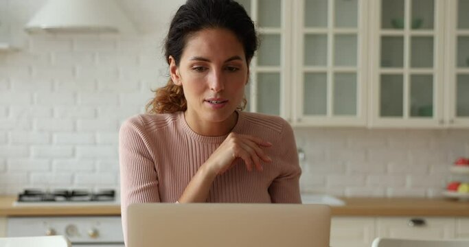 Smiling beautiful millennial woman web surfing interesting information online on computer, improving knowledge at home. Happy female modern technology user communicating distantly on laptop indoors.