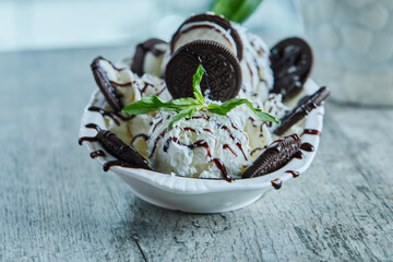Oreo ice-cream with chocolate syrup and mint in the white plate on the marble background