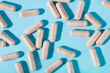 Vegetarian multivitamin capsules on a blue background. Food supplement, multivitamins, medicines, dietary fiber.