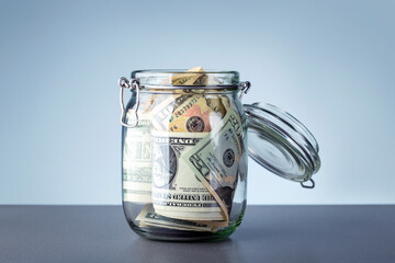 Glass jar with dollars money against grey background.  Donation and Saving Concept.