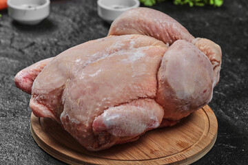 Raw whole chicken on wooden board. Close up