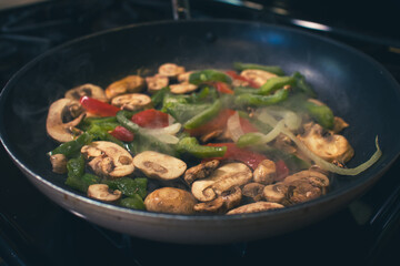 Steak peppers and onions being fried in a pan