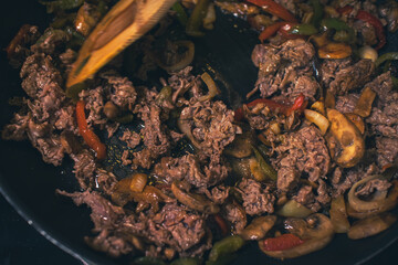 Steak peppers and onions being fried in a pan