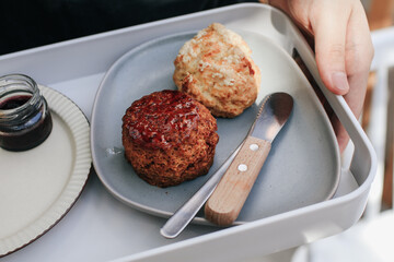 Delicious scones with Strawberry Jam, Clotted Cream and butter knife on a tray.