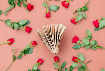 Book and red roses around on pink background