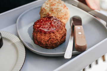 Delicious scones with Strawberry Jam, Clotted Cream and butter knife on a tray.